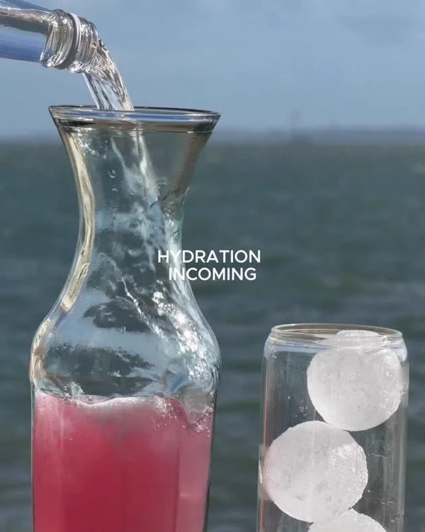 Water poured into a carafe of pink WILD WATER™ by the sea, captioned Hydration incoming