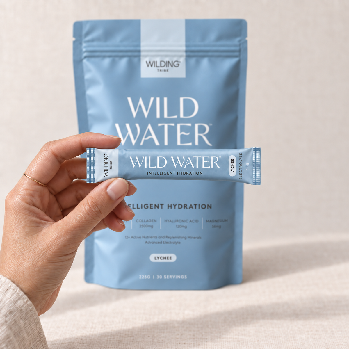 A hand holding a single WILD WATER™ sachet, with the pouch behind.